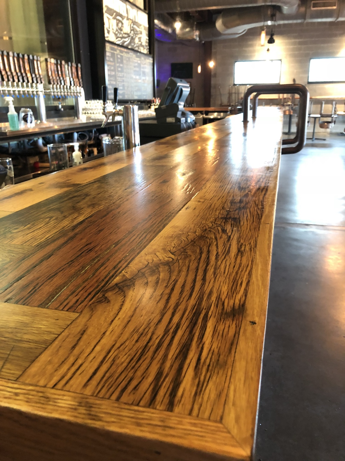 Long finished wood bar top with warm tones and pronounced grain in a restaurant interior